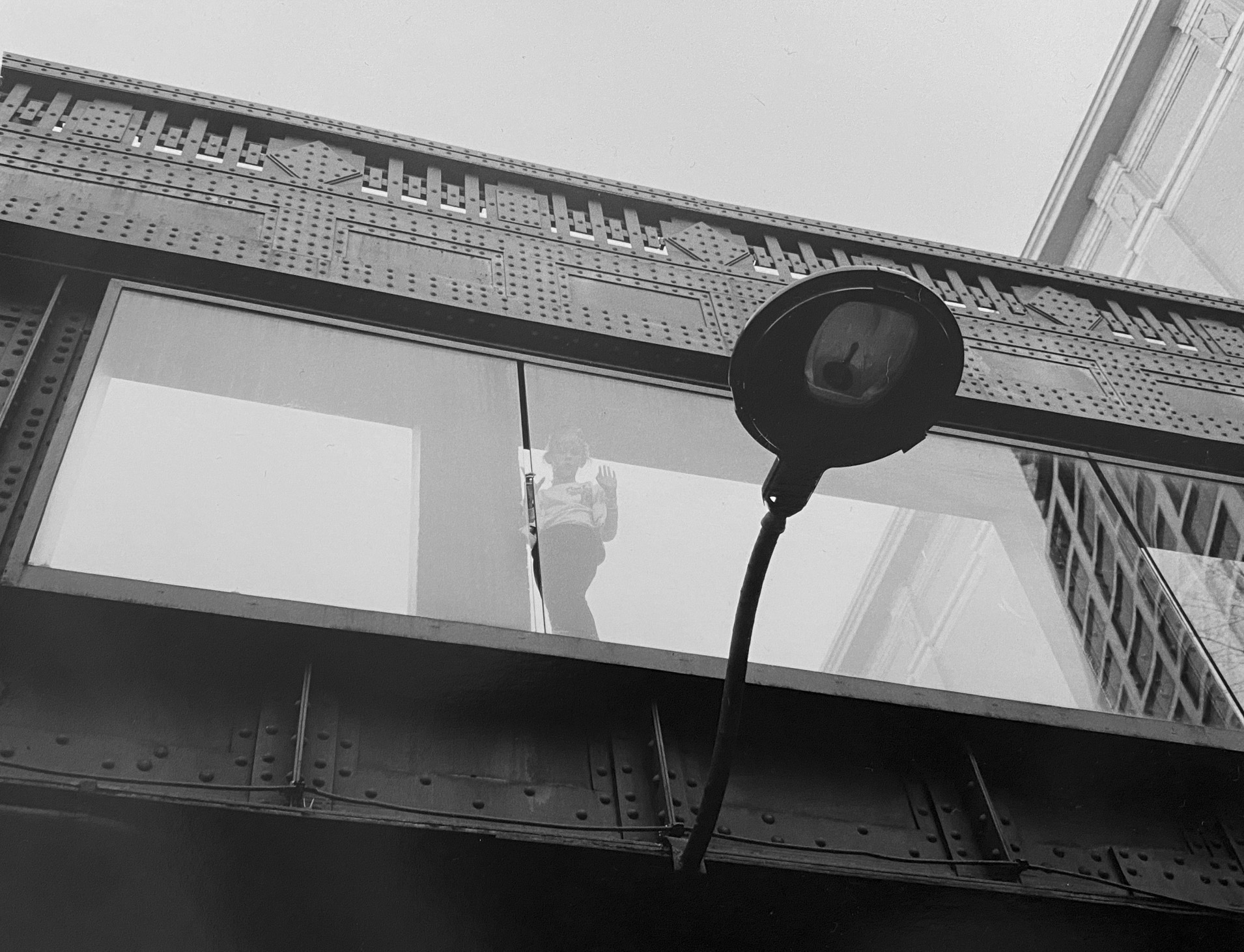 A person peers down through a glass-enclosed structure with an attached lamp